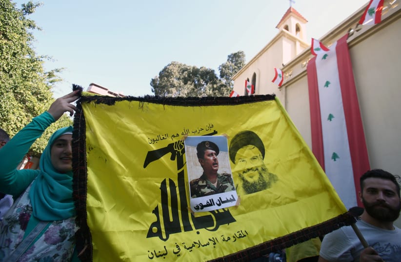 People carry a Hezbollah flag with a picture of newly appointed Lebanese President Michel Aoun stuck on it, in the Haret Hreik area, southern suburbs of Beirut, Lebanon October 31, 2016. (photo credit: REUTERS)