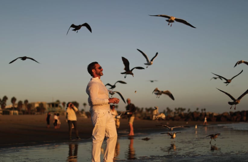 A MAN throws bread crumbs into the Pacific Ocean during the Tashlich prayer, a Rosh Hashana ritual to symbolically cast away sins, last week. (photo credit: REUTERS)