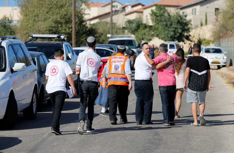 Medics and people at the scene where a Palestinian gunman killed three Israelis guards and wounded a fourth in a shooting attack  (photo credit: AMMAR AWAD / REUTERS)