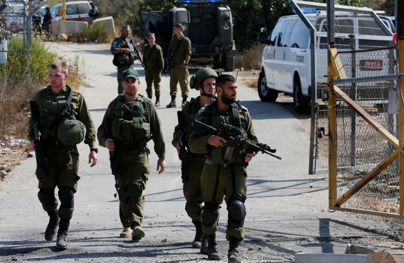 Israeli soldiers guard near the scene where a Palestinian gunman killed three Israelis and wounded a fourth in an attack on Har Adar before himself being shot dead, September 26, 2017. (photo credit: REUTERS)