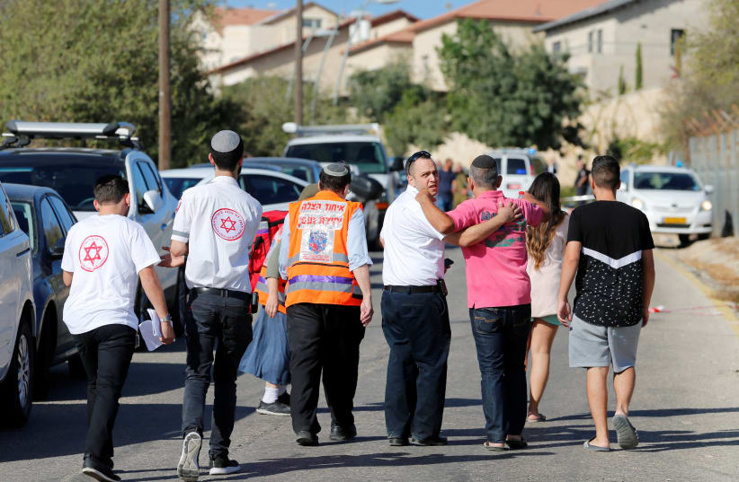 Medics and people walk at the scene where a Palestinian gunman killed three Israelis guards and wounded a fourth in an attack in Har Adar before himself being shot dead, September 26, 2017. (photo credit: REUTERS)