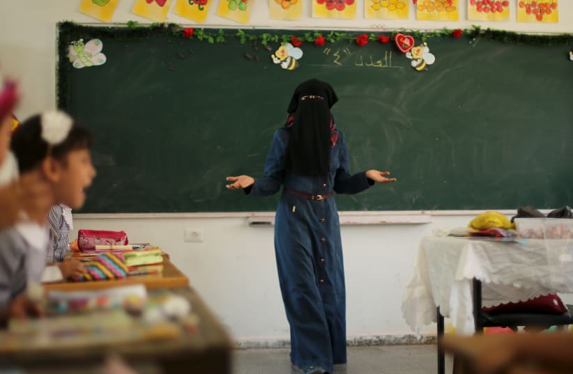 A veiled Palestinian teacher gestures as children attend a lesson at a United Nations Relief and Work Agency (UNRWA)-run school in Gaza (photo credit: REUTERS)
