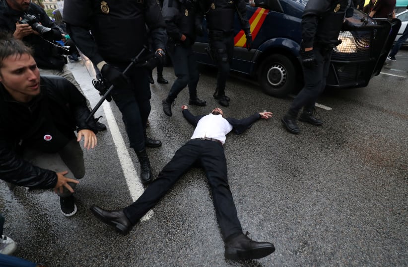 Riot police remove demonstrators outside a polling station for the banned independence referendum in Barcelona, Spain, October 1, 2017. (photo credit: REUTERS)