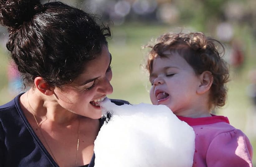 Mother and daughter enjoy cotton candy at Jewish holiday festivities.  (photo credit: MARC ISRAEL SELLEM/THE JERUSALEM POST)