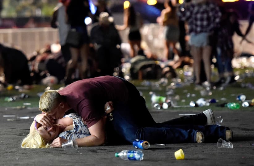 LAS VEGAS, NV - OCTOBER 01: A man lays on top of a woman as others flee the Route 91 Harvest country music festival grounds after a active shooter was reported on October 1, 2017 in Las Vegas, Nevada. (photo credit: DAVID BECKER/GETTY IMAGES/AFP)