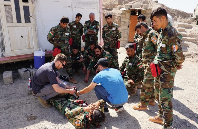 AN FAI VOLUNTEER shows Peshmerga how to apply a tourniquet at a base at Hawija, Iraq. (photo credit: SETH J. FRANTZMAN)