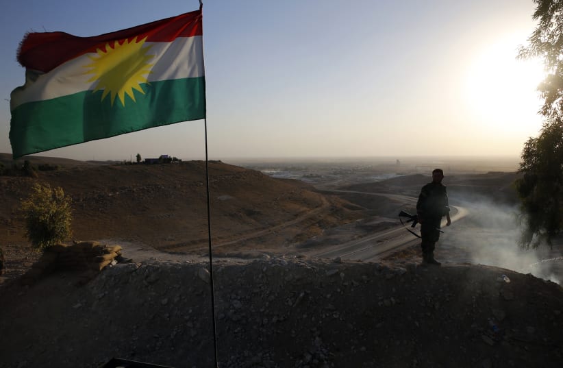 A Kurdish Peshmerga fighter looks down the road to Makhmur  (photo credit: AHMED JADALLAH / REUTERS)