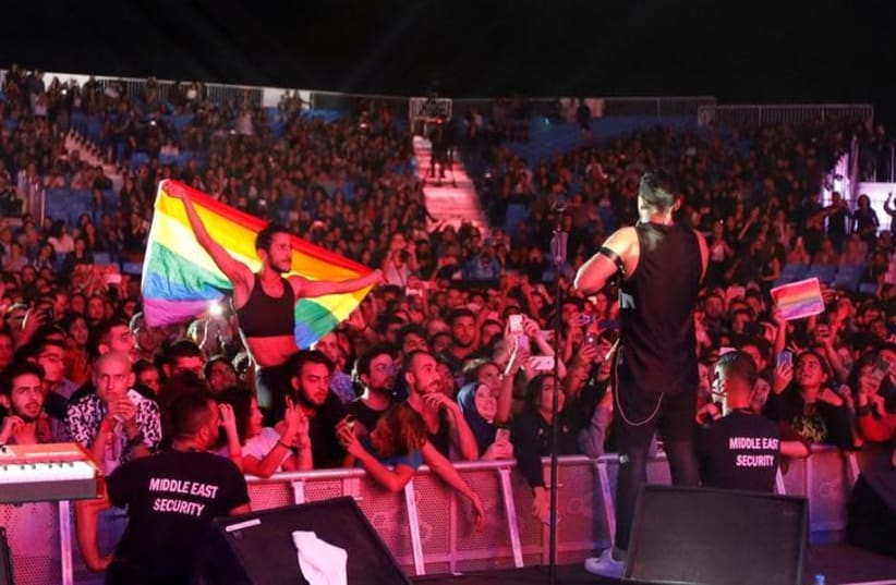 A fan of Lebanese alternative rock band Mashrou' Leila holds a rainbow flag during their concert at the Ehdeniyat International Festival in Ehden town, Lebanon August 12, 2017.  (photo credit: REUTERS/JAMAL SAIDI)