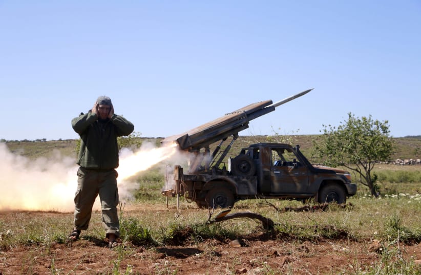 A Syrian rebel fires at forces loyal to Bashar Assad in Idlib, Syria  (photo credit: STRINGER/ REUTERS)