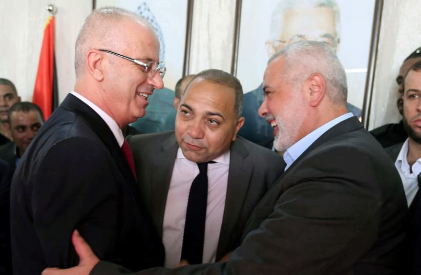 PALESTINIAN AUTHORITY Prime Minister Rami Hamdallah (left) shakes hands with Hamas chief Ismail Haniyeh in Gaza City on October 2. (photo credit: IBRAHEEM ABU MUSTAFA / REUTERS)