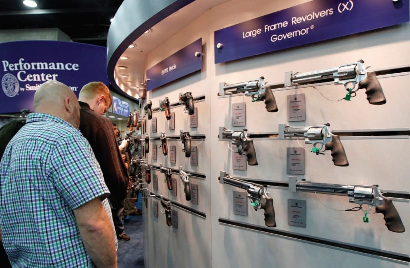 GUN ENTHUSIASTS look over Smith & Wesson guns at the National Rifle Association’s annual meetings and exhibits show in Louisville, Kentucky, last year. (photo credit: JOHN SOMMERS II / REUTERS)