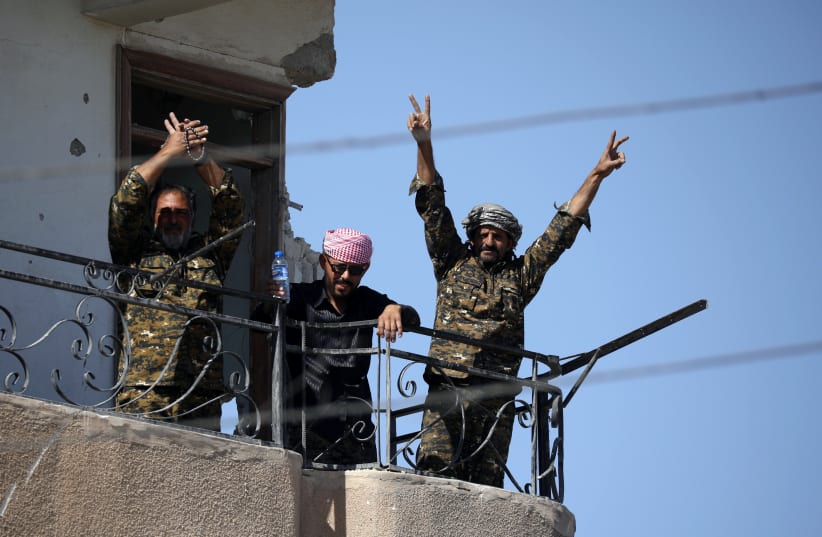 Fighters of Syrian Democratic Forces gesture the "V" sign at the frontline in Raqqa, Syria October 16, 2017.  (photo credit: REUTERS)
