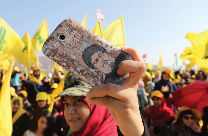A HEZBOLLAH supporter shows off a picture of leader Sayyed Hassan Nasrallah on her phone during a rally marking the 10th anniversary of the end of Hezbollah’s 2006 war with Israel, in Bint Jbeil, southern Lebanon (photo credit: REUTERS)