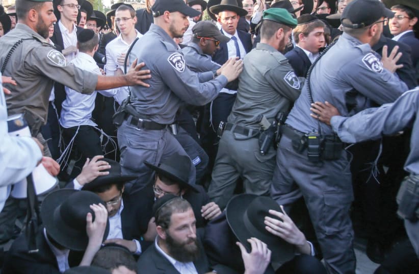 Police clear opponents of of IDF service from the tracks near the Jerusalem Light Rail’s Haturim Station yesterday. (photo credit: MARC ISRAEL SELLEM/THE JERUSALEM POST)