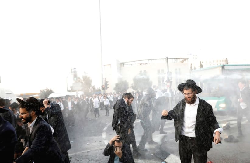 Water-canon spray hits ultra-orthodox protesters during demonstrations in the capital yesterday.  (photo credit: RONEN ZVULUN/REUTERS)