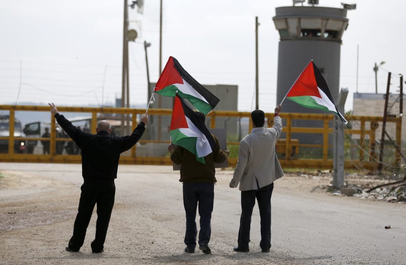 Palestinian protesters wave their national flag outside of an Israeli prison (photo credit: ABBAS MOMANI / AFP)