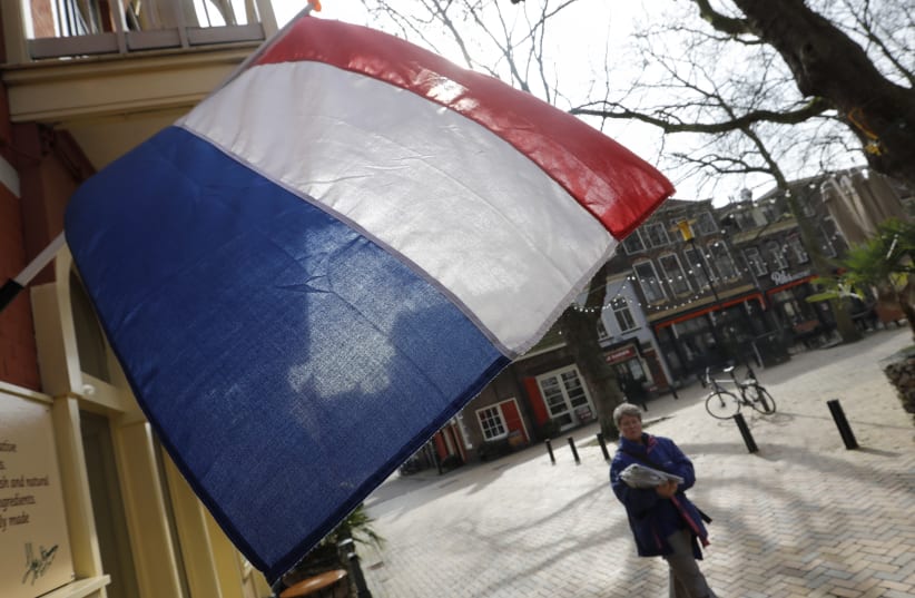 A woman walks past a national flag, the day before a general election, in Delft, Netherlands, March 14, 2017. (photo credit: REUTERS)
