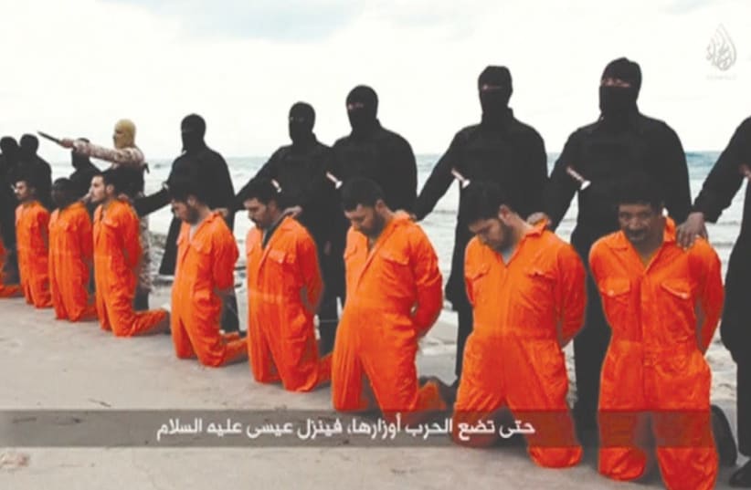 A STILL IMAGE from a video shows men, purported to be Egyptian Christians held captive by Islamic State, kneeling before armed men on a beach in Tripoli, Libya, in 2015. (photo credit: REUTERS)