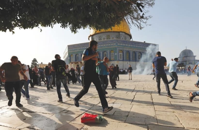 Palestinians react as stun grenades explode on the Temple Mount in Jerusalem’s Old City during riots at the site on July 27. (photo credit: REUTERS/MUAMMAR AWAD)