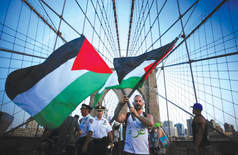 A MAN holds two flags as demonstrators at a 2014 pro-Palestinian rally march across the Brooklyn Bridge in New York City (photo credit: REUTERS/EDUARDO MUNOZ)