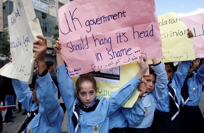 Palestinian children hold signs protesting the UK's acknowledgment and celebration of the Balfour Declaration cenetennial in mass protests.  (photo credit: MOHAMAD TOROKMAN/REUTERS)