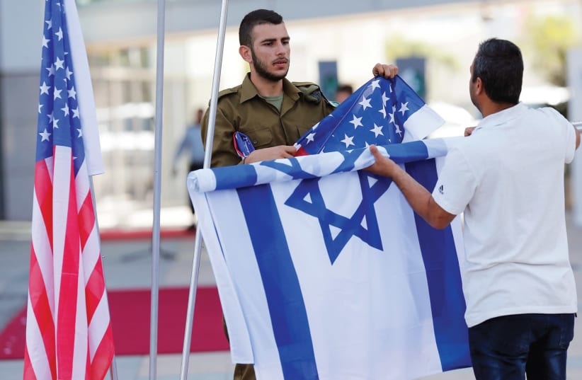 An Israeli soldier arranges Israeli and American flags (photo credit: REUTERS)