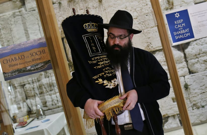 Rabbi Ari Edelkopf holds a Torah scroll at one of several prayer centers set up to cater to Jewish visitors to the 2014 Sochi Winter Olympic Games in Russia. (photo credit: REUTERS/MIKE SEGAR)