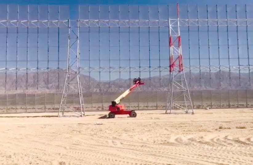 Workers in a ‘cherry-picker’ lend a sense of scale to the smart fence being installed around the country’s newest civilian airport currently under construction (photo credit: DEFENSE MINISTRY)