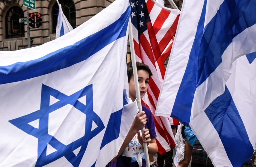 A boy is surrounded by Israeli and American flags (photo credit: REUTERS/STEPHANIE KEITH)