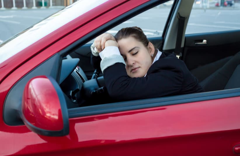 A woman asleep in the driver's seat of her car (photo credit: INGIMAGE)