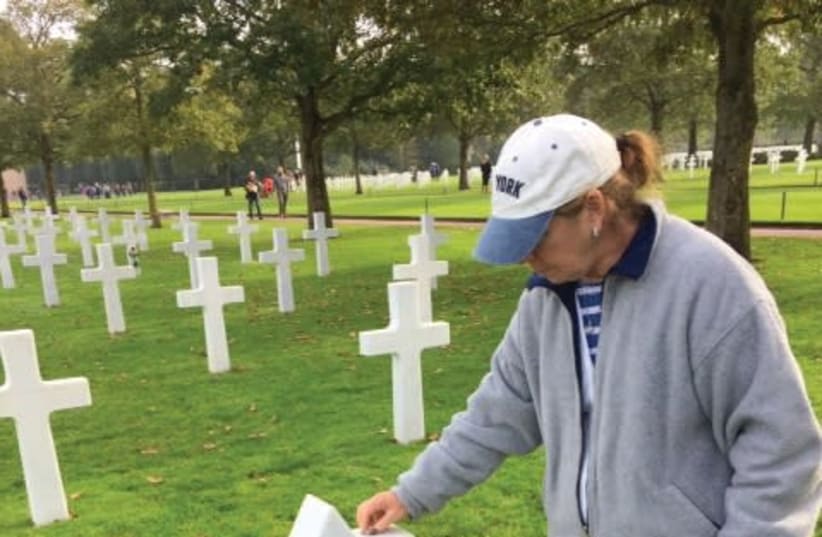 A VISITOR to the American military cemetery in Normandy places a stone on the grave of one of the 300 Jewish soldiers interred there. (photo credit: STEWART WEISS)