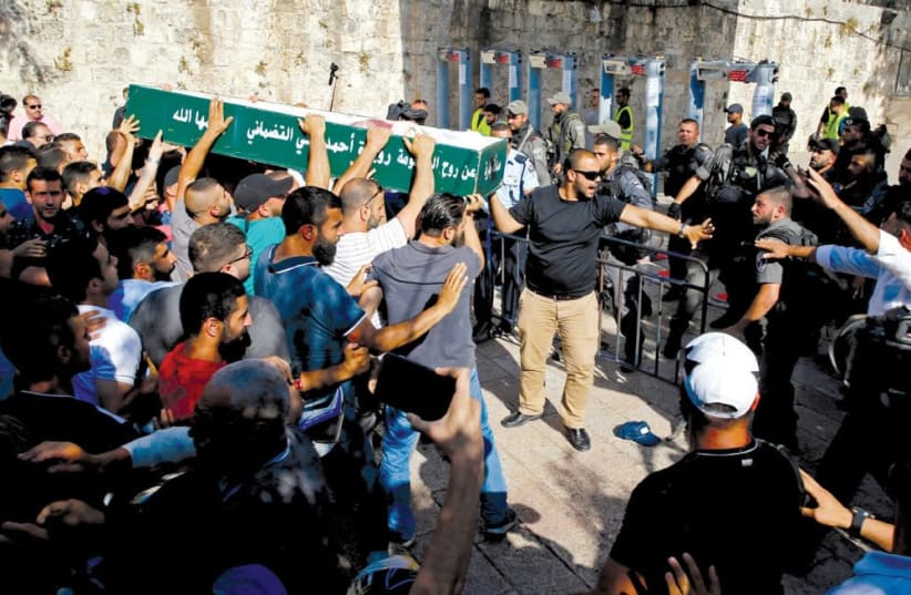 MUSLIMS ARGUE with Border Police officers as they carry a coffin at an entrance to the Temple Mount on July 16, wishing to hold a funeral inside the Aksa Mosque. (photo credit: AMMAR AWAD / REUTERS)