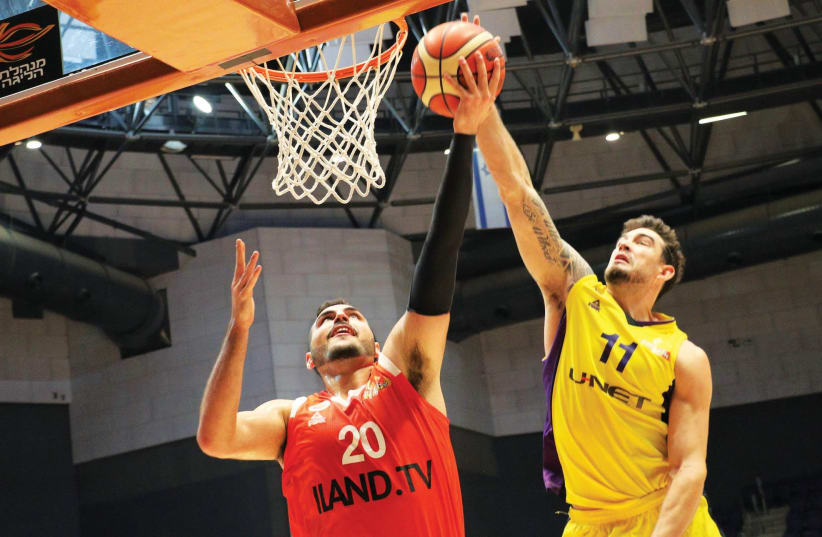 Hapoel Holon forward Joe Alexander (right) registers one of his two blocks on Maccabi Rishon Lezion center Idan Zalmanson (left) during last night’s 104-74 home conquest, with the American also finishing with a BSL career-high of 29 points. (photo credit: ADI AVISHAI)