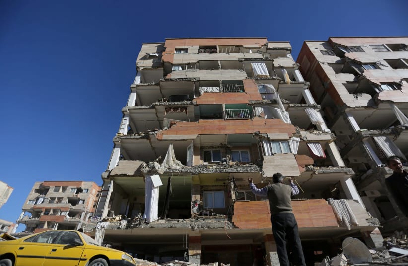 A man reacts as he looks at a damaged building following an earthquake in Iran (photo credit: REUTERS/TASNIM NEWS AGENCY)