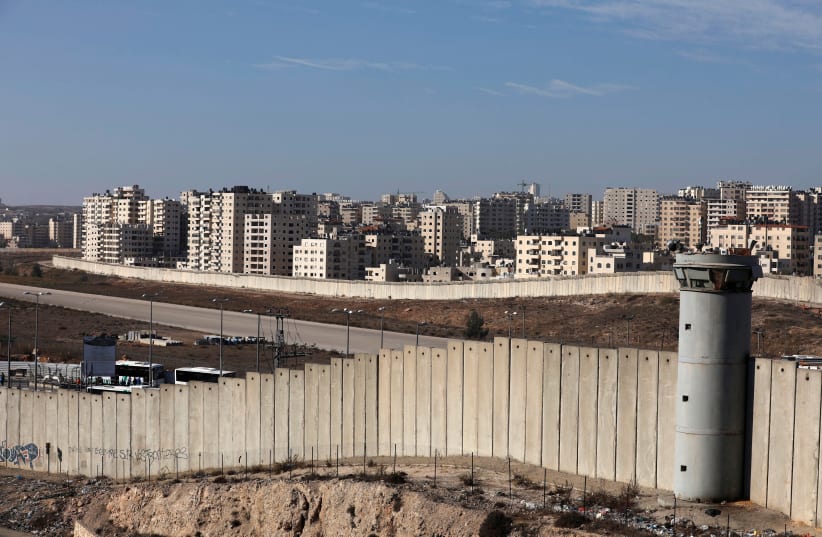 A view shows the Israeli barrier as buildings are seen in Kfar Aqab on the outskirts of Jerusalem, near the West Bank City of Ramallah, November 7, 2017. (photo credit: REUTERS/MOHAMAD TOROKMAN)