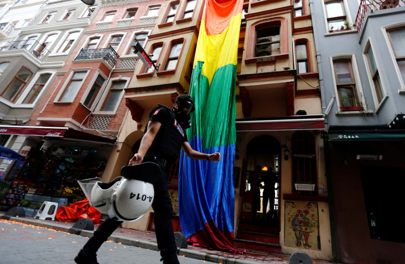 A riot police, with a rainbow flag in the background, chases LGBT rights activists as they try to gather for a pride parade, which was banned by the governorship, in Istanbul, Turkey (photo credit: REUTERS/MURAD SEZER)