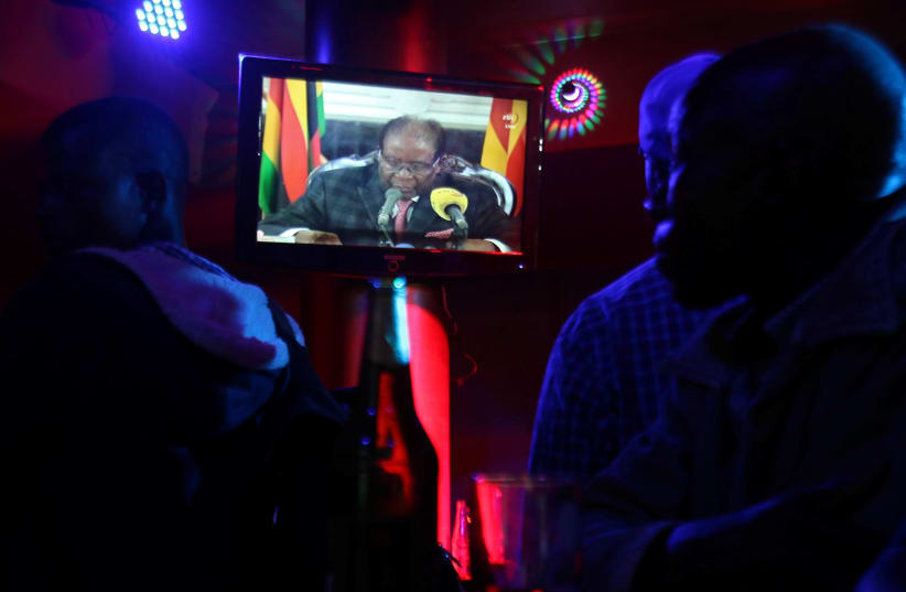 People watch as Zimbabwean President Robert Mugabe addresses the nation on television, at a bar in Harare, Zimbabwe, November 19, 2017 (photo credit: REUTERS/PHILIMON BULAWAYO)