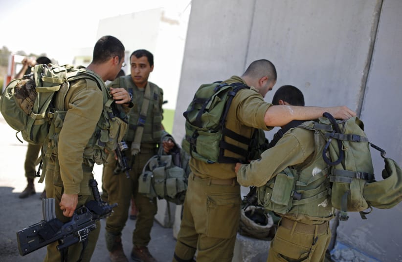 Israeli soldiers wear their combat gear near a shelter at Kerem Shalom crossing August 1, 2014. (photo credit: AMIR COHEN - REUTERS)