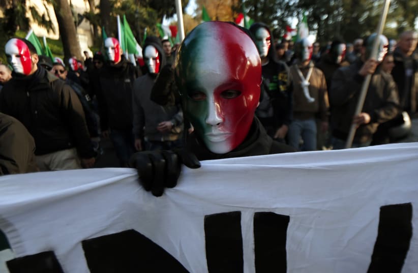 A member of Casapound far-right organization wears a mask in the colours of the Italian flag before a demonstration in Rome (photo credit: YARA NARDI / REUTERS)