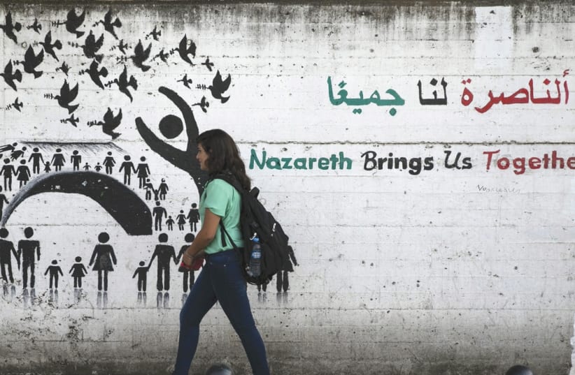 A YOUTH walks past graffiti on a street in Nazareth. (photo credit: REUTERS)
