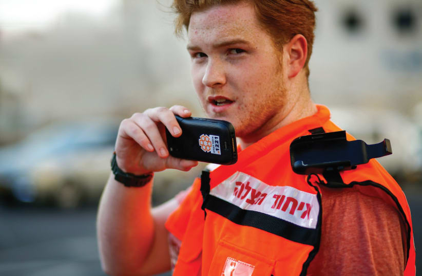 A UNITED HATZALAH volunteer holds the new smartphone mobile device that will be issued to all of the organization’s volunteers. (photo credit: COURTESY UNITED HATZALAH)