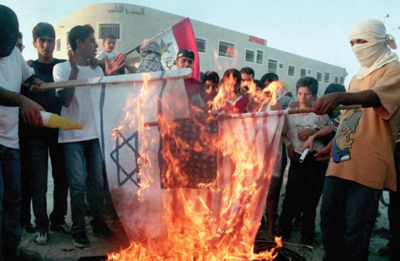 PALESTINIAN DEMONSTRATORS burn American and Israeli flags on the top of a symbolic coffin with the words ‘Oslo accords’ written on it in September 1993. (Reuters) (photo credit: REUTERS)