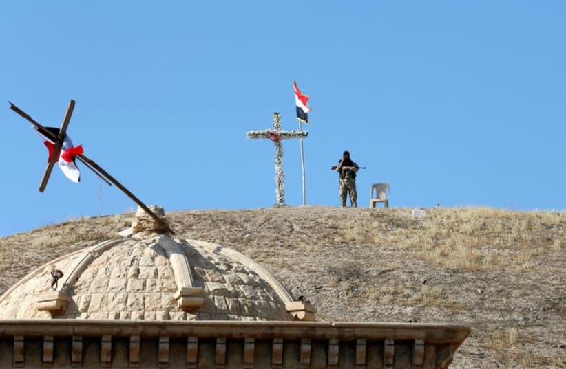 An Iraqi Christian soldier guards the church of Saint Barbara after it was recaptured from Islamic State, near Mosul (photo credit: AHMED JADALLAH / REUTERS)