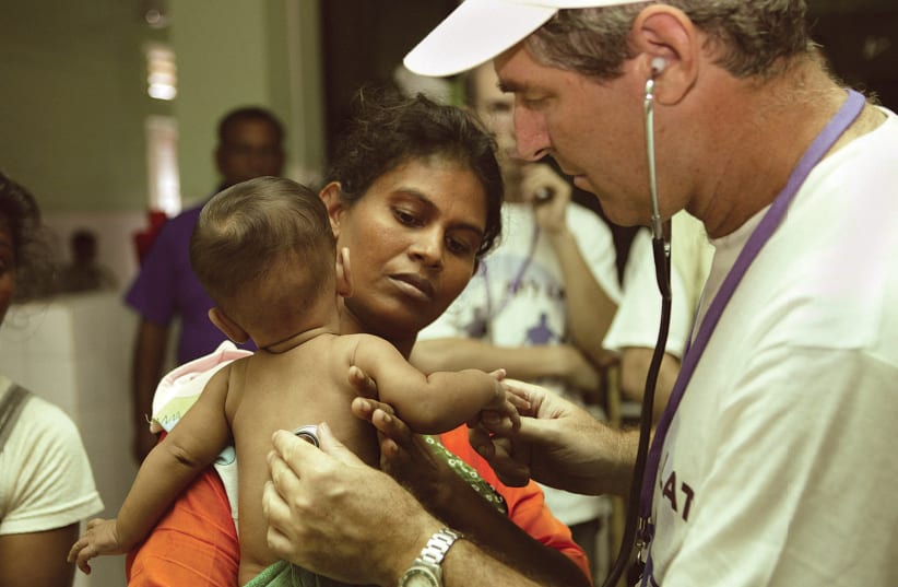 SHEBA MEDICA CENTER’S Prof. Eli Schwartz, a world specialist in tropical diseases, treats a child in Sri Lanka following the 2004 tsunami (photo credit: Courtesy)