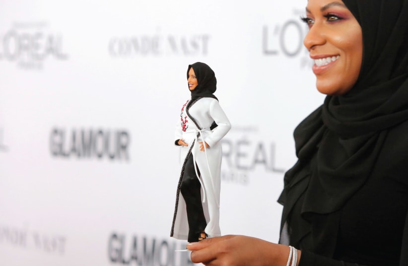 Olympic fencer Ibtihaj Muhammad poses with a barbie doll made in her likeness (photo credit: REUTERS)