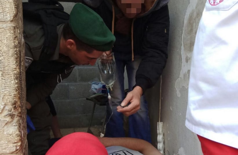 Israeli Border Police treating a Palestinian man who fell unconscious in Hebron. (photo credit: ISRAEL BORDER POLICE SPOKESMAN)