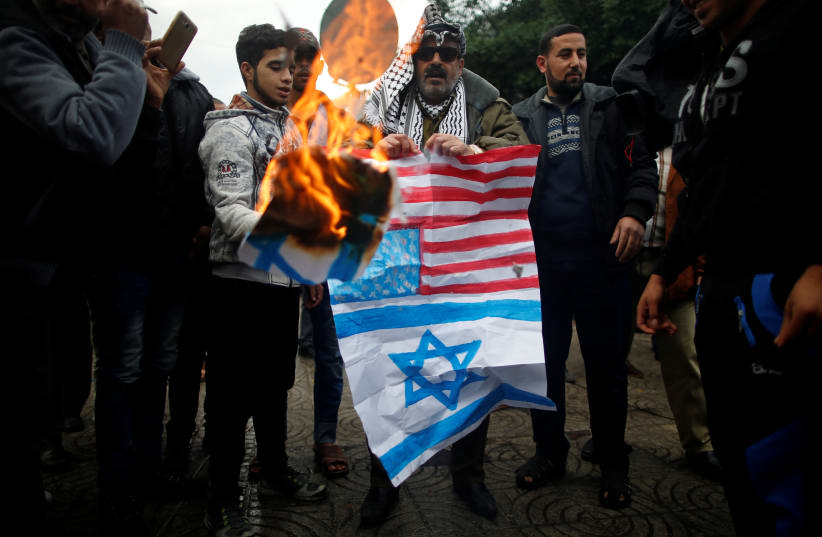 Palestinians burn signs depicting an Israeli flag and a U.S. flag during a protest against the U.S. intention to move its embassy to Jerusalem and to recognize the city of Jerusalem as the capital of Israel, in Gaza City December 6, 2017. (photo credit: MOHAMMED SALEM/REUTERS)