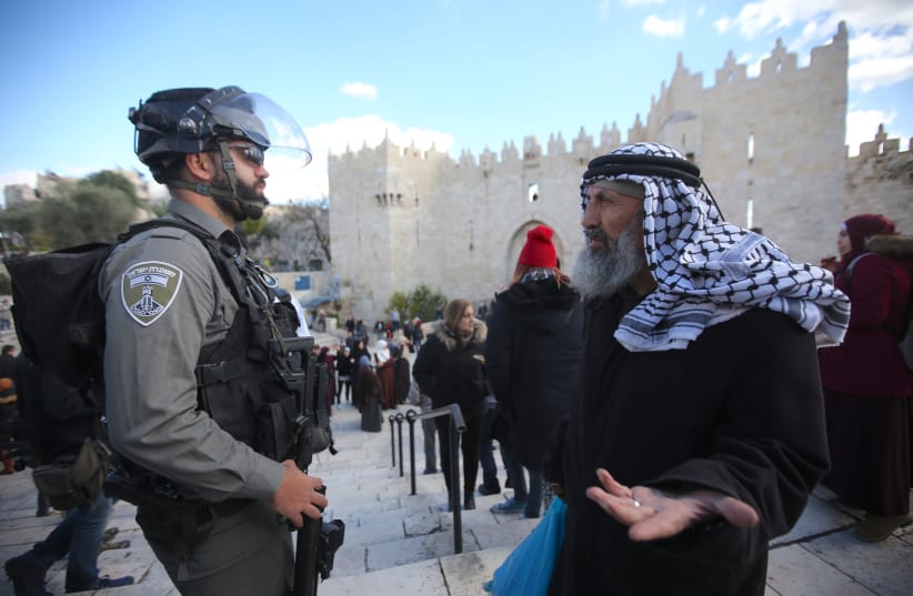 Man wearing keffiyah with Israeli security officer outside the Damascus gate in the Old City of Jerusalem. (photo credit: MARC ISRAEL SELLEM)