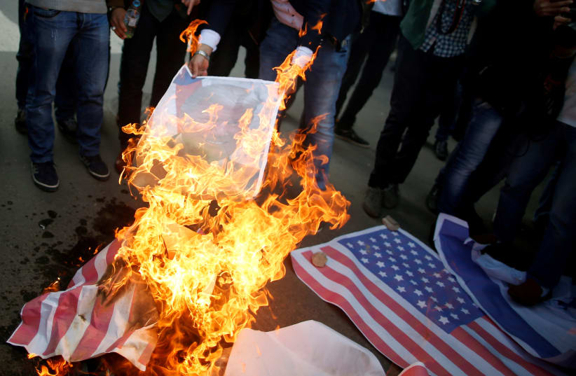 Palestinian protesters burn a poster depicting US President Donald Trump and a representation of a US flag during a protest against Trump's decision to recognize Jerusalem as the capital of Israel, in Gaza City  (photo credit: MOHAMMED SALEM/ REUTERS)