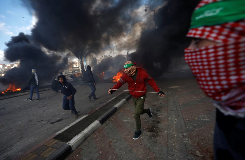 Palestinian protesters run during clashes with Israeli troops at a protest near the Jewish settlement of Beit El, near the West Bank city of Ramallah December 7, 2017. (photo credit: REUTERS)